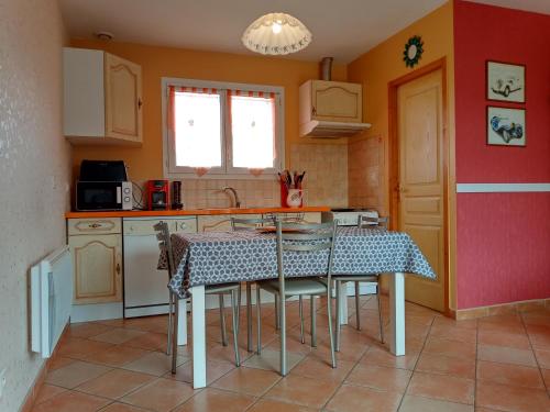 a kitchen with a table and chairs in a room at Au petit lieu-dit in Anglade