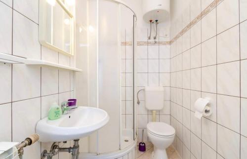La salle de bains blanche est pourvue de toilettes et d'un lavabo. dans l'établissement Apartments Tatjana Crikvenica, à Crikvenica