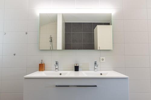 a white bathroom with a sink and a mirror at Nesserduinen in Nes