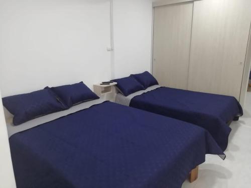 2 camas en una habitación con sábanas azules en Hospedaje maderos en Armenia