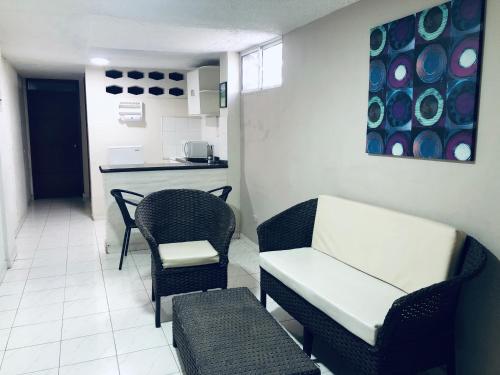 a living room with chairs and a couch and a kitchen at Hotel Boston Superior in Barranquilla