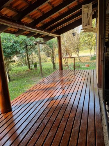 a wooden deck with a view of a field at Sítio com piscina Hidromassagem com acesso ao Rio Mampituba in Passo de Torres