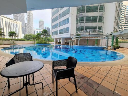 una piscina con 2 sillas y una mesa frente a un edificio en Crest Residence Klcc Bukit Bintang by Sarah's Lodge, en Kuala Lumpur
