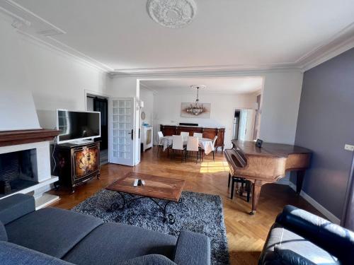 een woonkamer met een bank en een piano bij Villa Pougeol - Charmante Villa Calme & Paisible - Avec Piscine & Terrain de Pétanque in Chanac-les-Mines