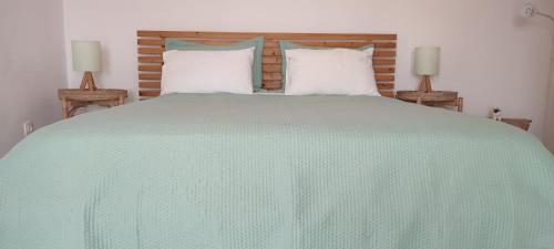 a large bed with a green comforter and two lamps at Sofia sea view house in Faros