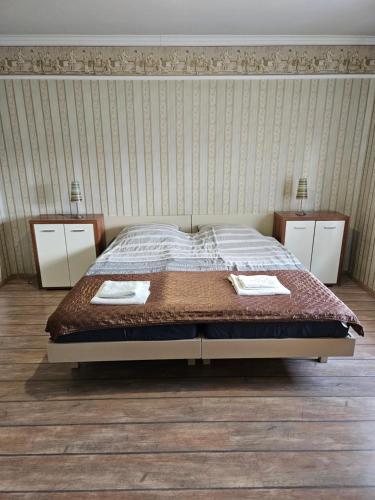a bedroom with a large bed with two night stands at Fenyves Apartman in Tiszafüred