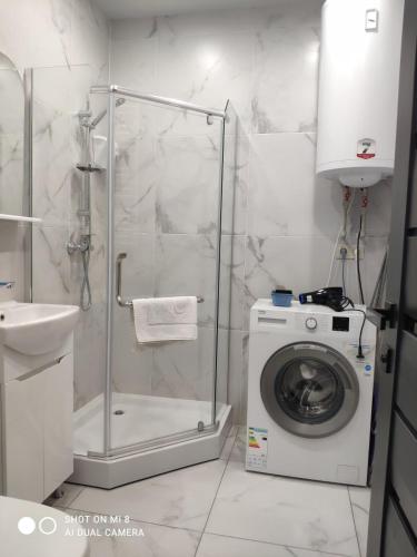 a bathroom with a washing machine and a shower at Apartments Domovik Миру 11с /11 in Mukacheve