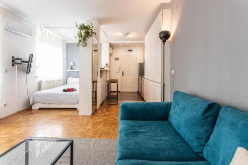 a living room with a blue couch and a bedroom at Lovely Studio with a big terrace in Belgrade