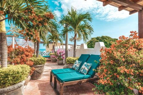 卡塔赫納的住宿－卡爾塔科薩酒店，一个带蓝色长椅和棕榈树的庭院