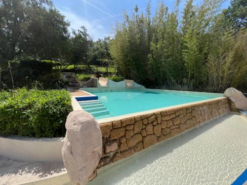 une piscine entourée d'un mur en pierre dans l'établissement AZUR APPARTEMENT (SEA VIEW) LES RESTANQUES DE ST-TROPEZ1131, à Grimaud