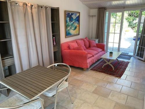 sala de estar con sofá rojo y mesa en Gîte tout confort (SPA, Sauna, piscine chauffée), en Saint-Vivien