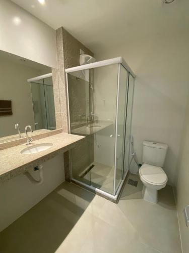 La salle de bains est pourvue d'une douche en verre et de toilettes. dans l'établissement Le Coin - MDJ, à Cabo Frio