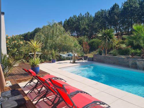 une piscine avec deux chaises et une piscine dans l'établissement Maison sud des Landes proche Seignosse/ Capbreton / Soustons, à Tosse