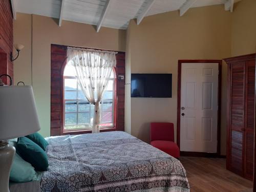 a bedroom with a bed and a window and a red chair at Eden Crest Villa in Anse La Raye