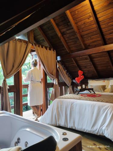 a woman standing next to a tub in a bedroom at Cabanas dos Plátanos in Gramado