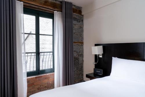 a bedroom with a bed and a window at Le Petit Hotel Notre Dame in Montréal