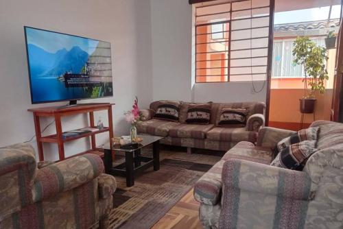 a living room with couches and a flat screen tv at APARTAMENTO URMA Cuzco in Cusco