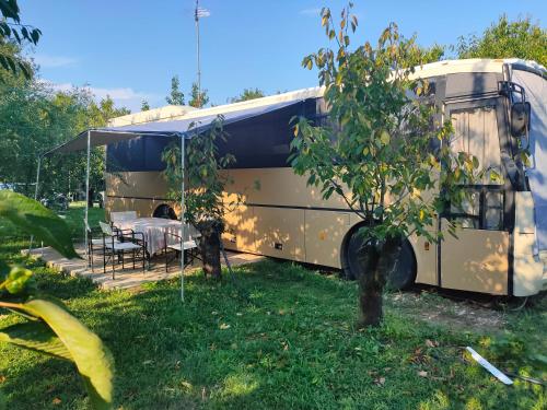 an rv parked in the grass with a table at terrebioBus in Visnadello