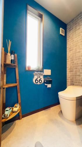 a bathroom with a toilet and a blue wall at Ocean Villa Vihara ヴィハーラ in Ōda