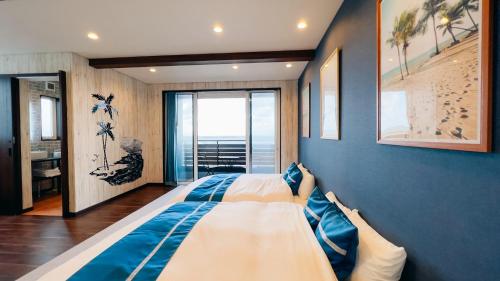een slaapkamer met 2 bedden en een blauwe muur bij Ocean Villa Vihara ヴィハーラ in Ōda