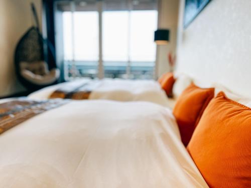 a bedroom with two beds with orange pillows and a window at Ocean Villa Vihara ヴィハーラ in Ōda