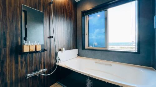 a bathroom with a bath tub and a window at Ocean Villa Vihara ヴィハーラ in Ōda