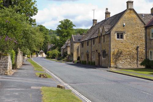 an empty street in a village with stone houses at Davenford Cotswold Gardens in Stow on the Wold