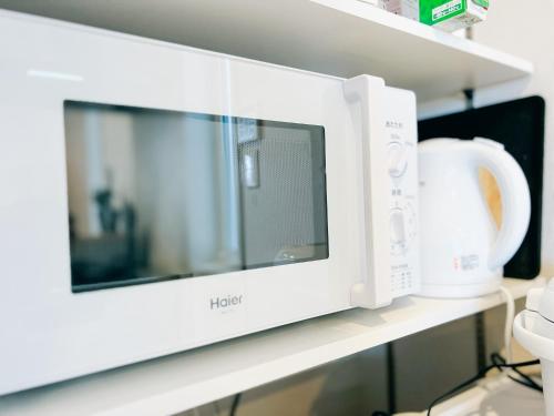 a microwave oven on a shelf in a kitchen at Ocean Villa Vihara ヴィハーラ in Ōda