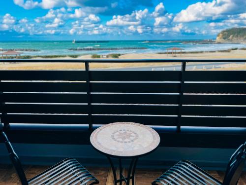 a table and chairs on a balcony with a view of the beach at Ocean Villa Vihara ヴィハーラ in Ōda