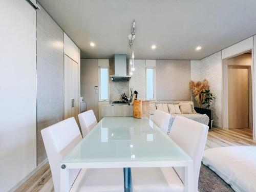 a white dining room with a white table and chairs at Ocean Villa Vihara ヴィハーラ in Ōda