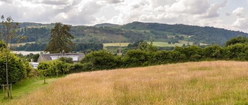 a grassy hill with a house in the middle of a field at Tayview Lodges in Pitlochry