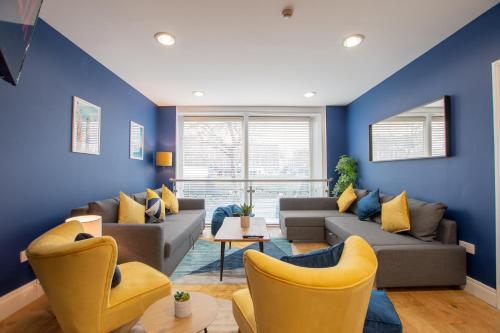 a living room with blue walls and yellow chairs at The Yellow Door by Shortstays in Dublin