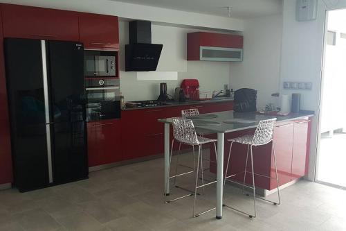 uma cozinha com armários vermelhos, uma mesa e cadeiras em Superbe appartement vue mer - résidence de standing em Schœlcher