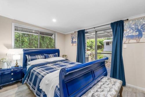 a bedroom with a blue bed and a window at Jardee Chateau Guest House in Conondale