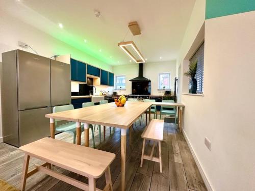 a kitchen with a table and chairs and a refrigerator at Massive New 8 bedroom House Sleeps up to 21 - Accepts Groups - Great Location - FREE Parking - Fast WiFi - Smart TVs - sleeps up to 21 people - Close to Bournemouth & Poole Town Centre & Sandbanks in Bournemouth