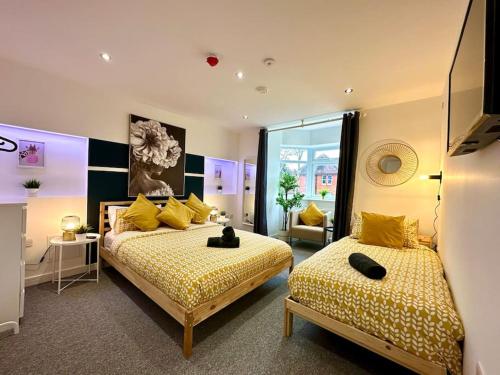 - une chambre avec 2 lits et des oreillers jaunes dans l'établissement Massive New 8 bedroom House Sleeps up to 21 - Accepts Groups - Great Location - FREE Parking - Fast WiFi - Smart TVs - sleeps up to 21 people - Close to Bournemouth & Poole Town Centre & Sandbanks, à Bournemouth
