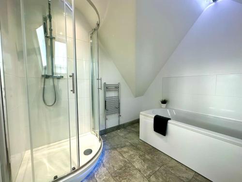 a white bathroom with a shower and a bath tub at Massive New 8 bedroom House Sleeps up to 21 - Accepts Groups - Great Location - FREE Parking - Fast WiFi - Smart TVs - sleeps up to 21 people - Close to Bournemouth & Poole Town Centre & Sandbanks in Bournemouth