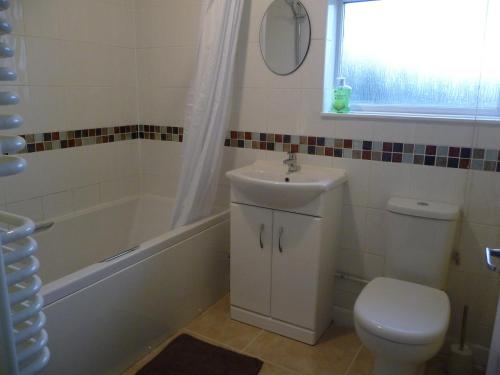 a bathroom with a sink and a tub and a toilet at Bright spacious home, enclosed garden & parking in Hindlip