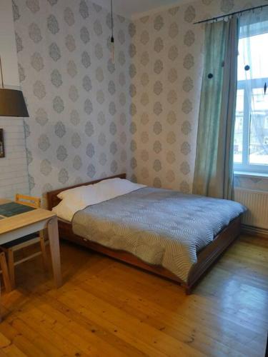 a bedroom with a bed and a table and a window at 550 метров до моря in Liepāja