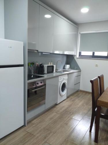 a kitchen with white cabinets and a washer and dryer at Retiro da Quinta do Souto in Peso da Régua