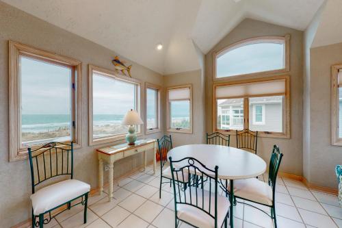 a dining room with a table and chairs and windows at Sand Goodies PI128 in Corolla