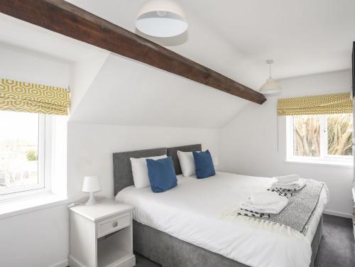 a bedroom with a white bed with blue pillows at Gorwel in Llanallgo