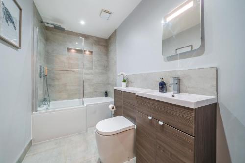 a bathroom with a toilet and a sink and a tub at Smart Living by Lawsons in Windsor