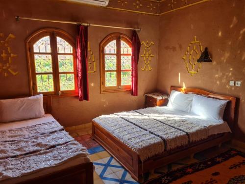 a bedroom with two beds and two windows at Hotel Awayou in Bou Drarar