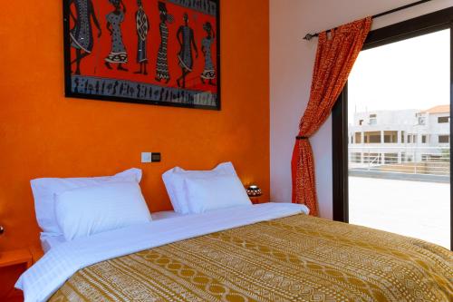 ein Schlafzimmer mit einem Bett mit orangefarbenen Wänden und einem Fenster in der Unterkunft ChezBabo Wellness Hotel in Ngaparou