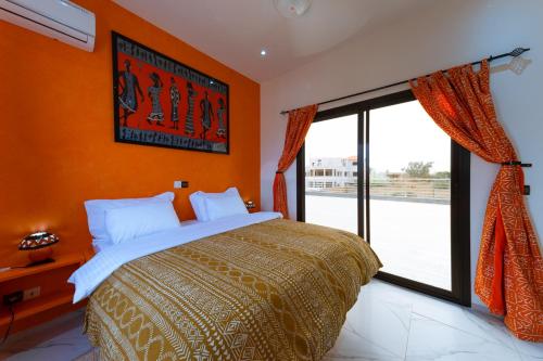 a bedroom with orange walls and a bed and a window at ChezBabo Wellness Hotel in Ngaparou