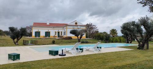 a villa with a swimming pool in front of a house at Monte das Hortas Velhas in Viana do Alentejo