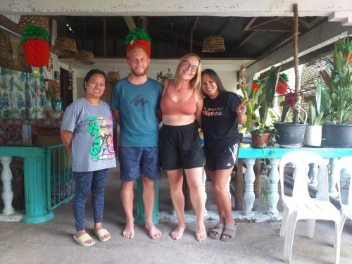 a family posing for a picture in front of a house at Paraiso Hostel Moalboal in Moalboal