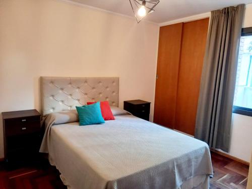 1 dormitorio con 1 cama con 2 almohadas de colores. en Dpto dos dormitorios en Nueva Córdoba en Córdoba