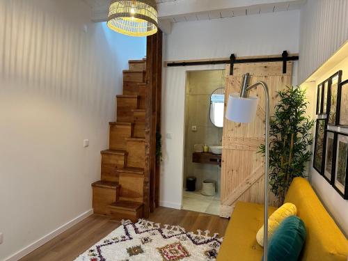 a living room with a yellow couch and a wooden staircase at Estoril Tiny Home 5 Minutes From the Beach in Estoril